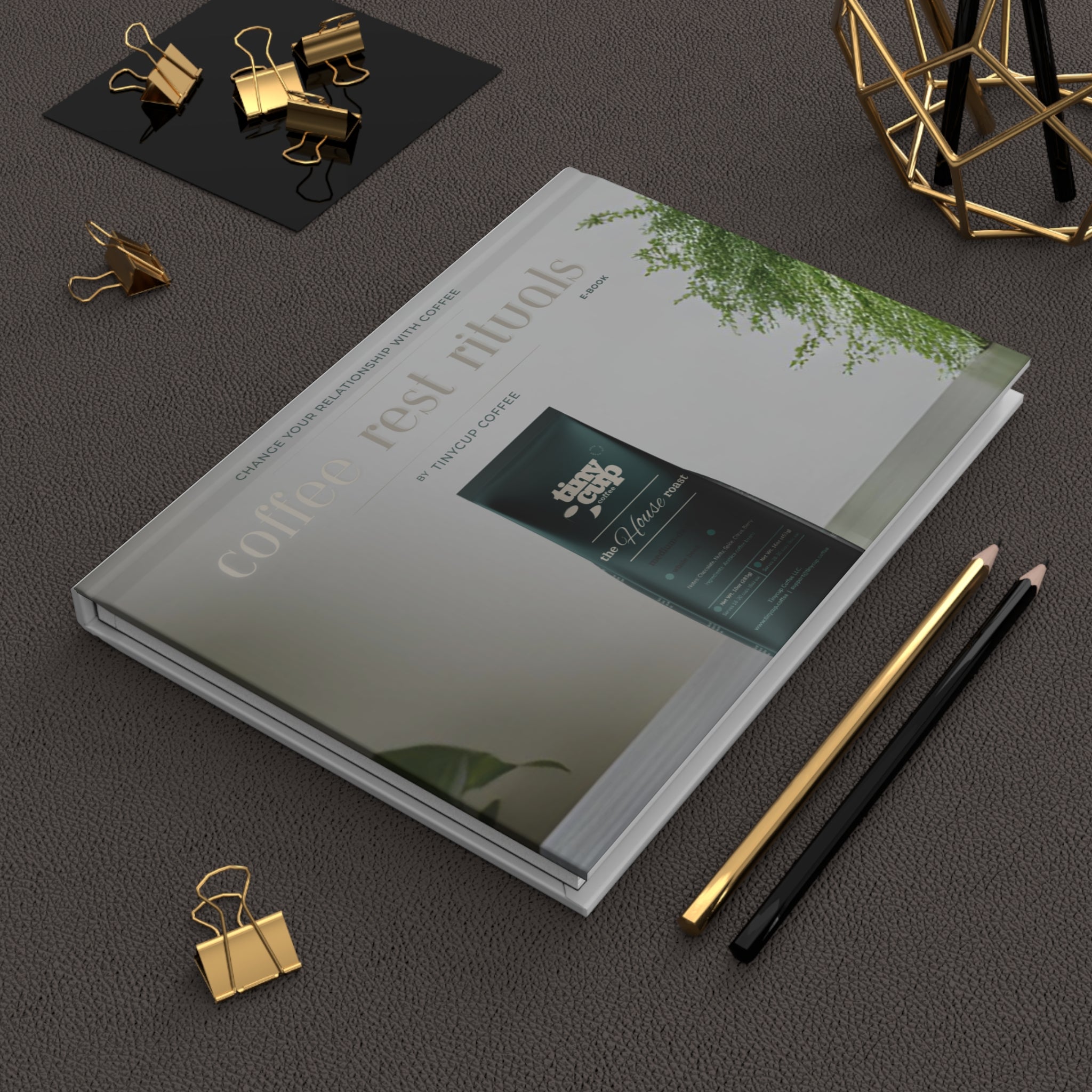 Notebook with a cover design on a dark surface with office supplies.